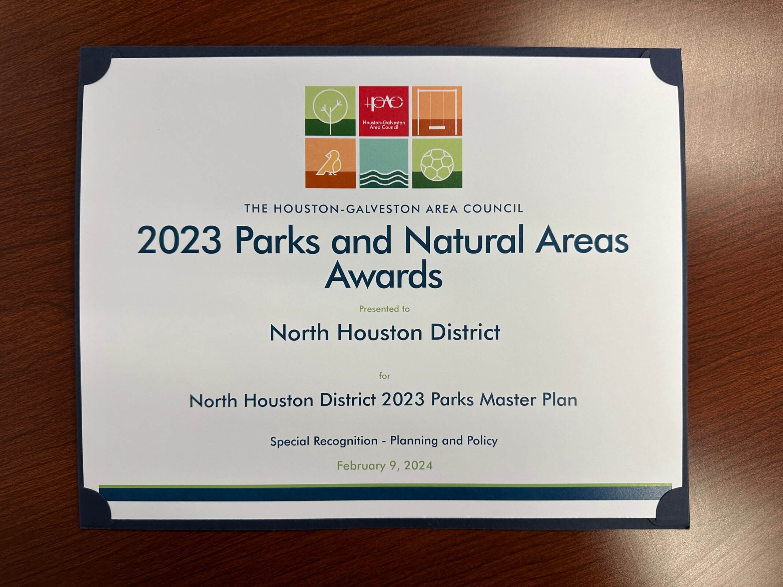 photo of a paper certificate sitting alone on a wooden table. The awards was received by the North Houston District for " 2023 Parks and Natural Areas Award" by Houston Galveston Area Council. 