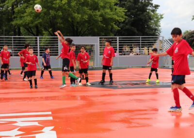 Real Greens Soccer Club kids in red uniforms playing soccer on a mini pitch